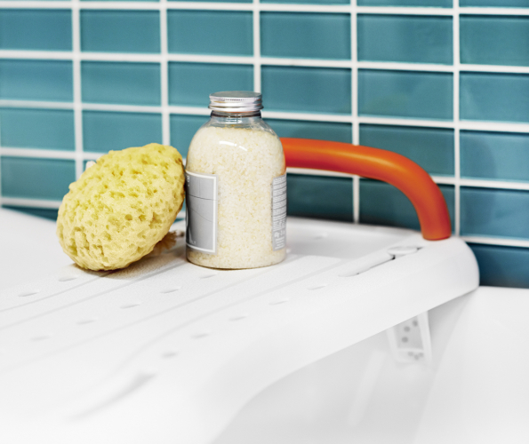 Picture of a bath board, a sponge and a bottle of bubble bath
