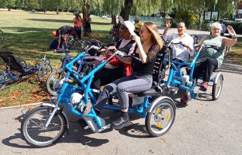 Group of people using accessible cycles smiling and waving