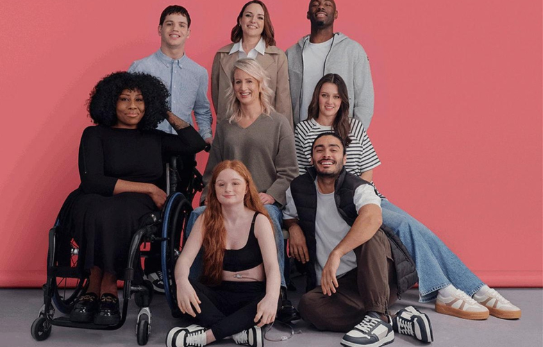 Picture of a group of men and women. They are wearing different types of Primark's adaptive clothing range. They are a mixed group in terms of impairments (wheelchair users) and backgrounds