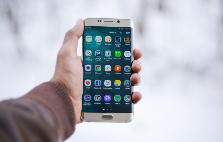 Handing holding a Samsung smartphone showing a number of different apps