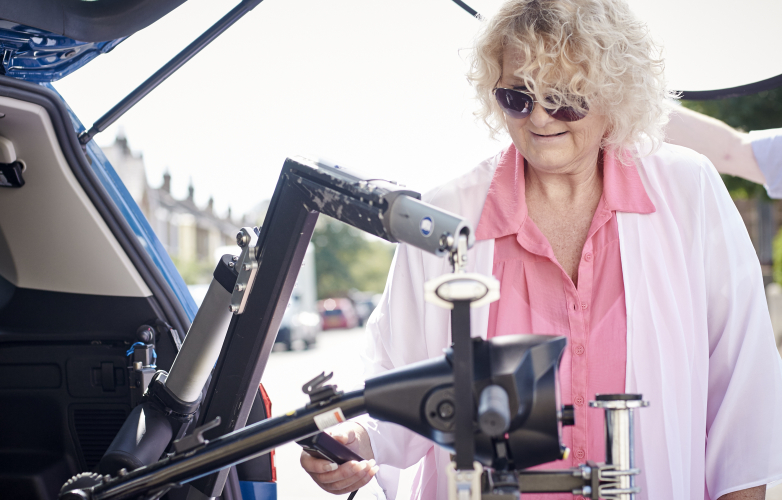 Woman using a boot hoist to load her mobility scooter into a car