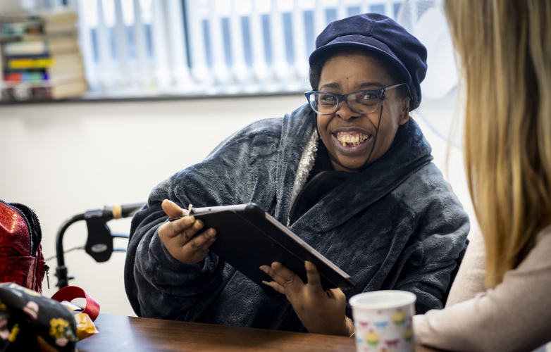 A smiling woman looking a tablet 