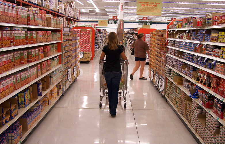 A woman walks through a supermarket pushing a trolley